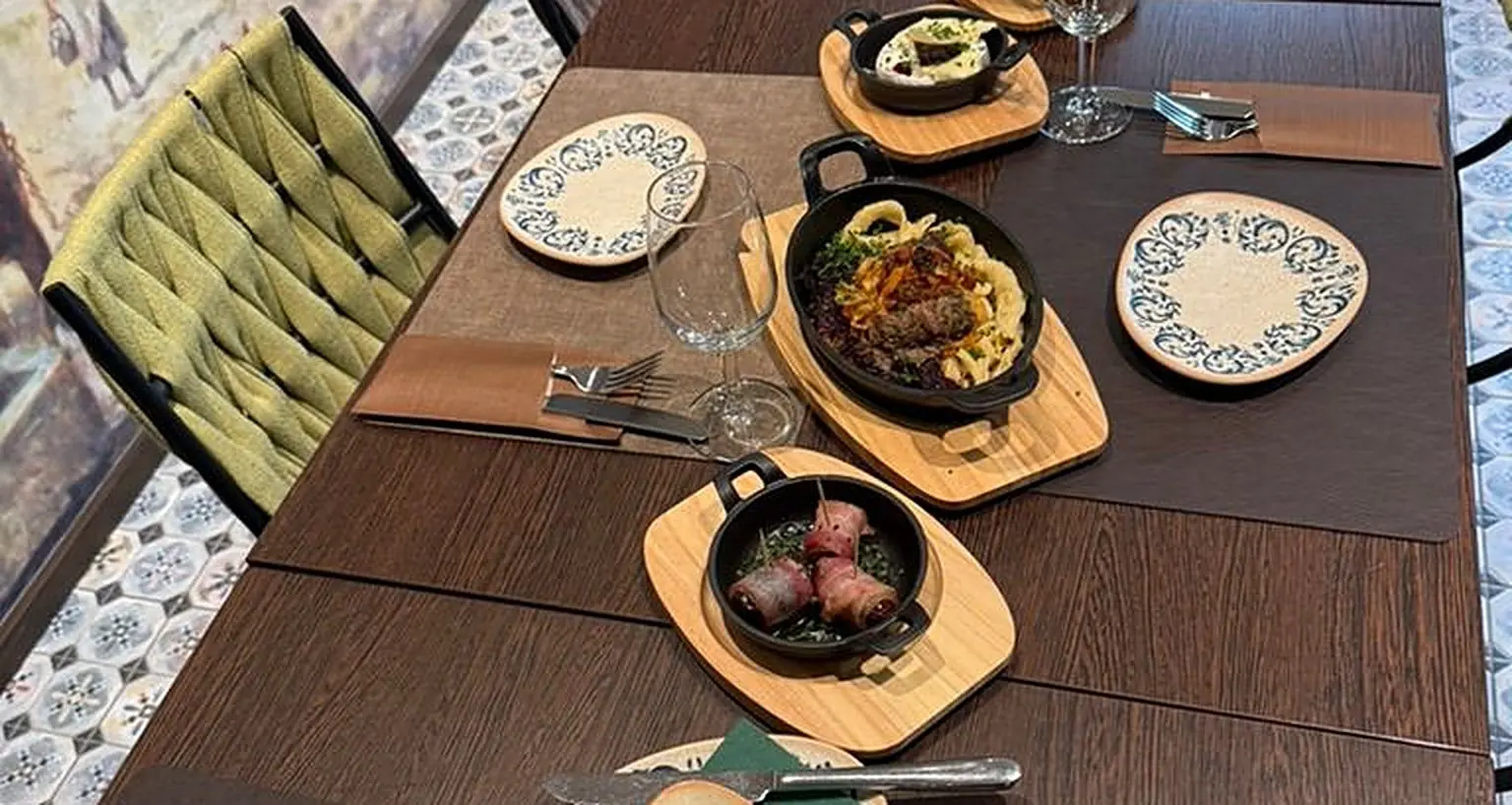 Deutsche Tapas in gusseisernen Pfännchen auf Holzbrettern am Tisch