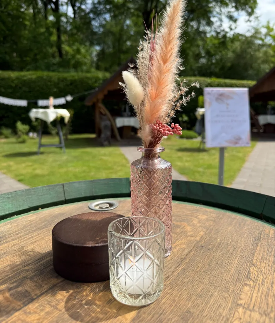 Fasstisch im Garten mit Trockenblumen und Windlicht