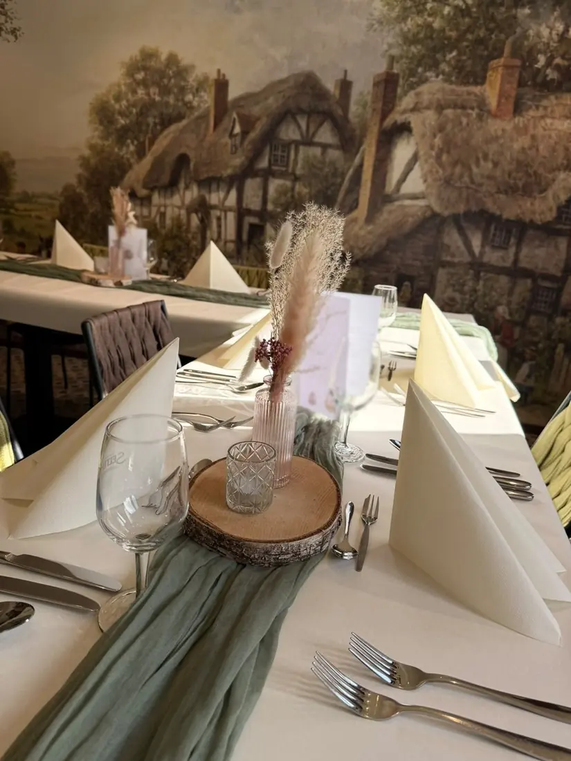 Festlich gedeckter Tisch mit grünem Läufer, Holzscheibe und Trockenblumen