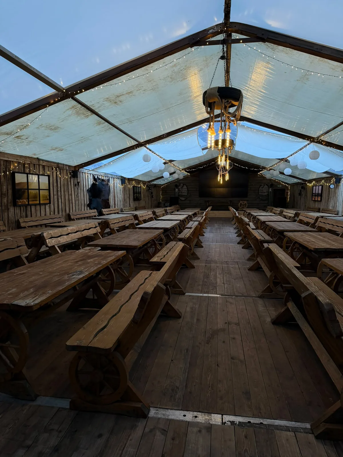 Unser Festzelt mit langen Holztafeln, Lichterketten und Leuchtern aus Seil