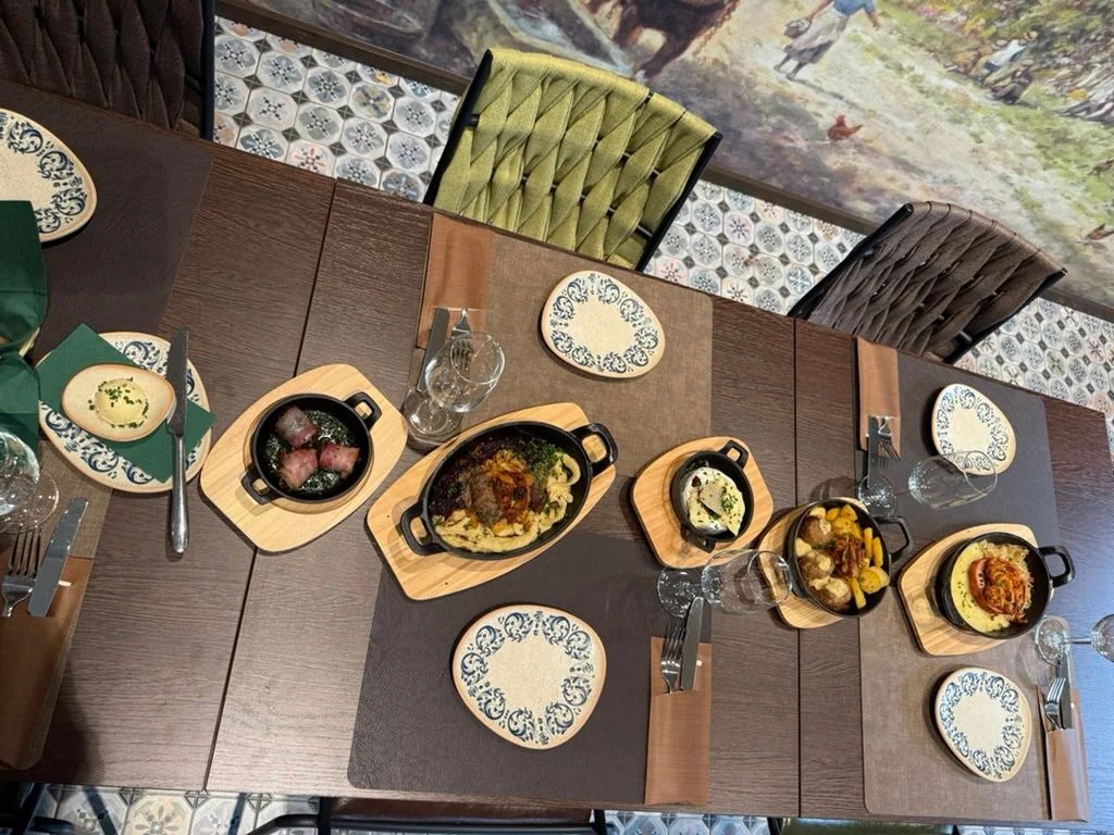 Gedeckte Tafel mit Deutschen Tapas in gusseisernen Pfännchen auf Holzbrettern