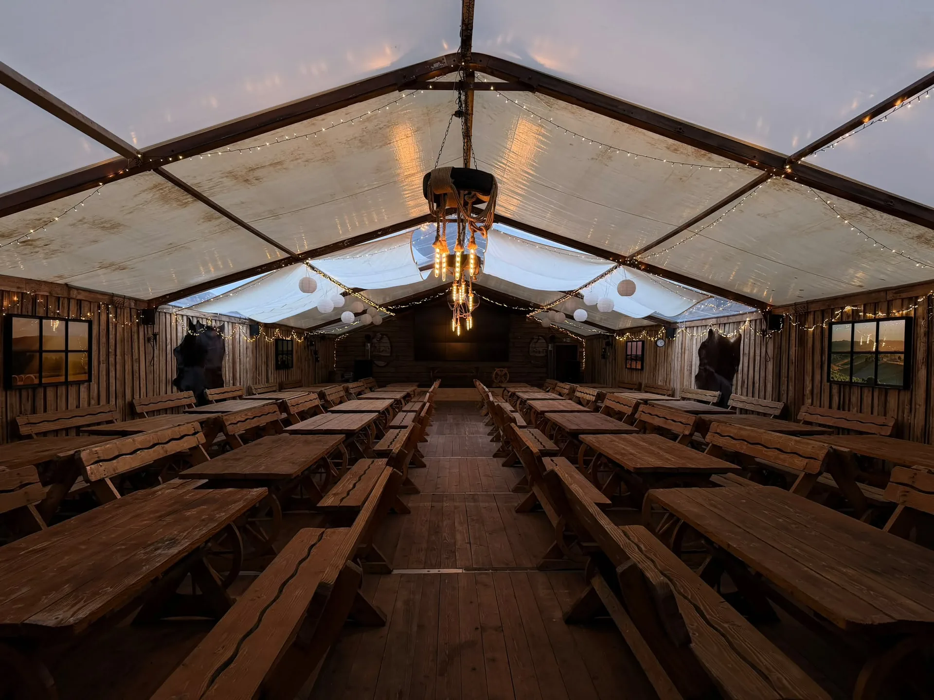 Unser Festzelt mit langen Holztafeln, Lichterketten und Leuchtern aus Seil